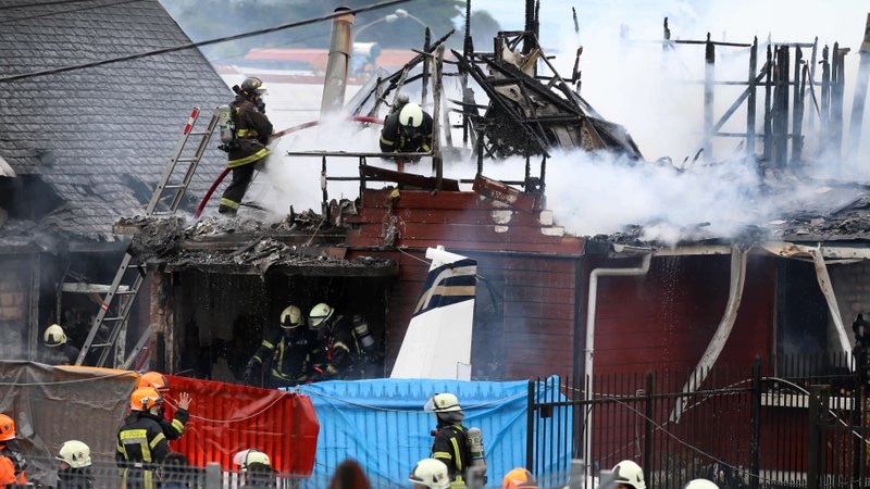 Firefighters work to put out the flames of a small plane that crashed into a house in Chile.