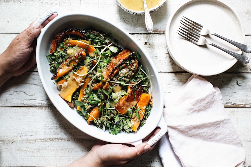 Roast pumpkin and lentil salad in a serving dish with a side of honey miso dressing, an easy recipe