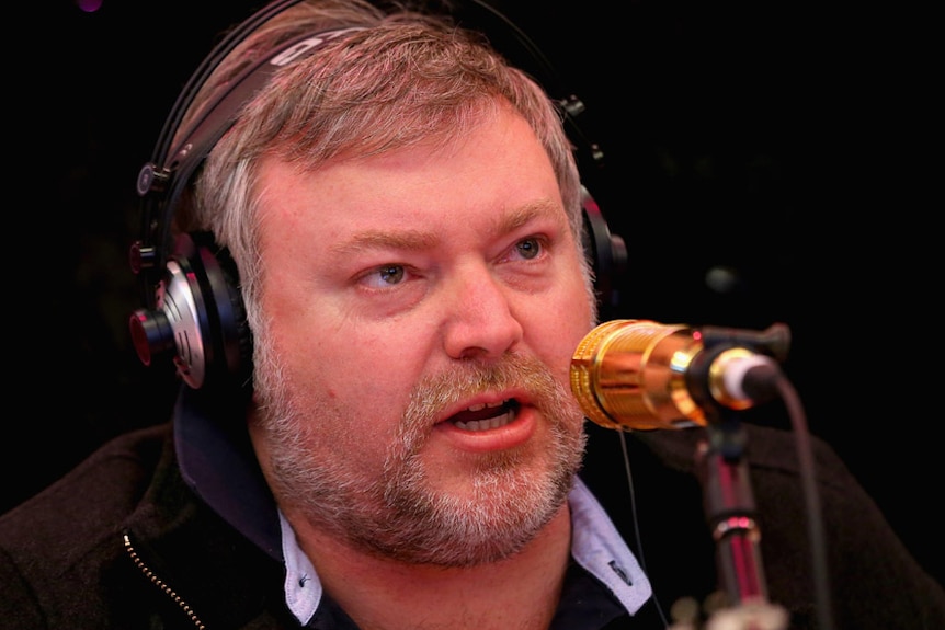 Radio presenter Kyle Sandilands speaking into his gold microphone