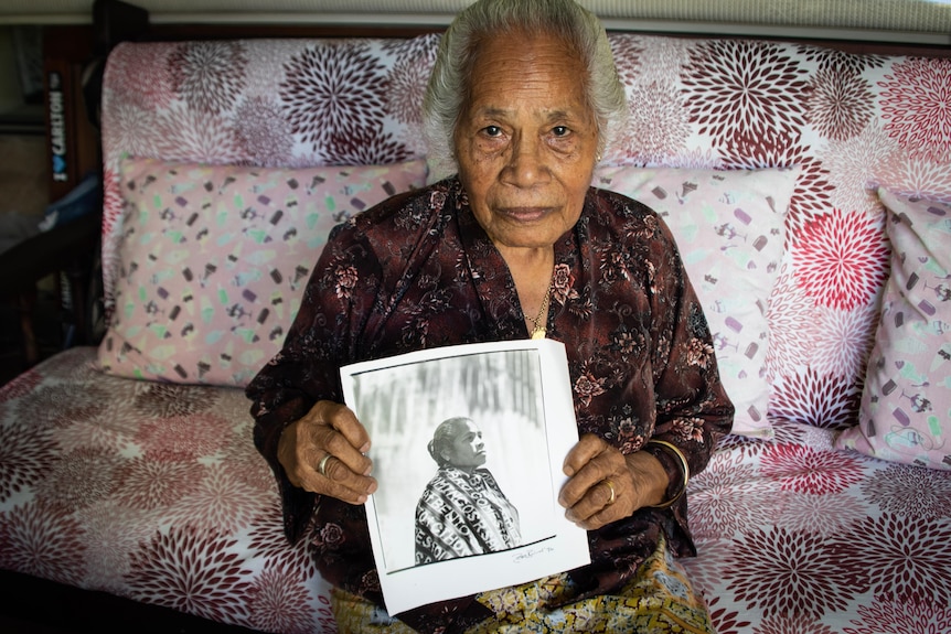 A portrait of an older lady holding a photo of her younger self.