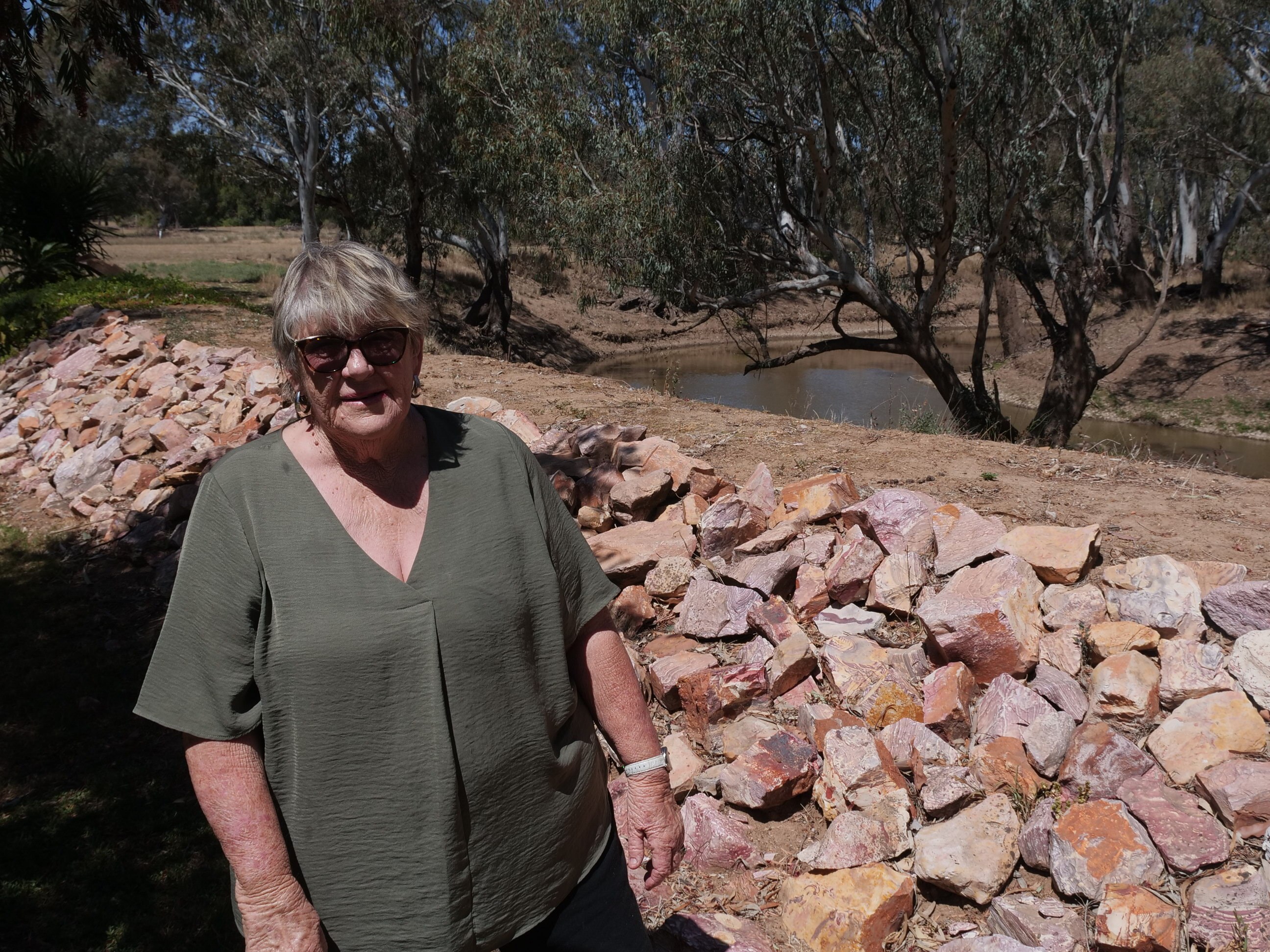 A woman standing next to some rocks near a river