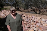 A woman standing next to some rocks near a river