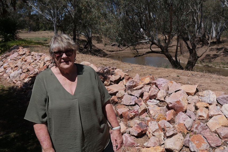 Una mujer parada junto a unas rocas cerca de un río.