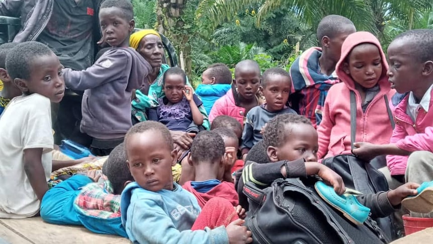 Children sit in the back of a vehicle. 