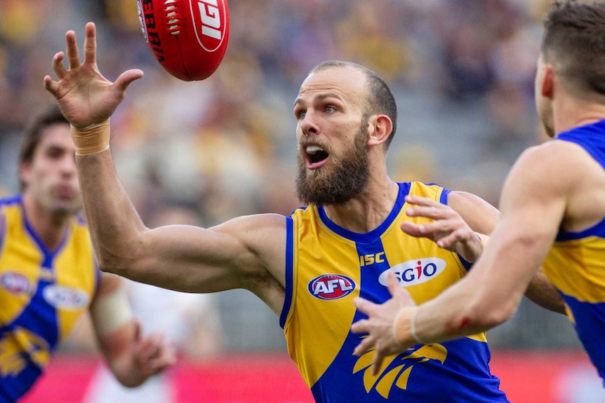 An Eagles player reaches for the football, supported by two colleagues.