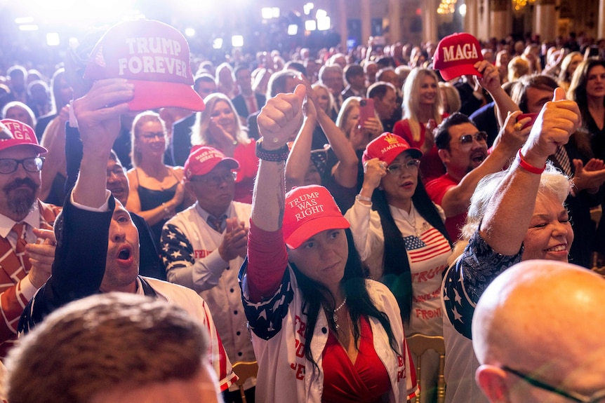 A group of Trump supporters raise their fists in support of the former president