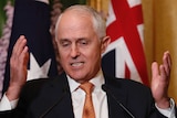 Prime Minister Malcolm Turnbull speaks with microphones in front of him, hands gesturing beside his face