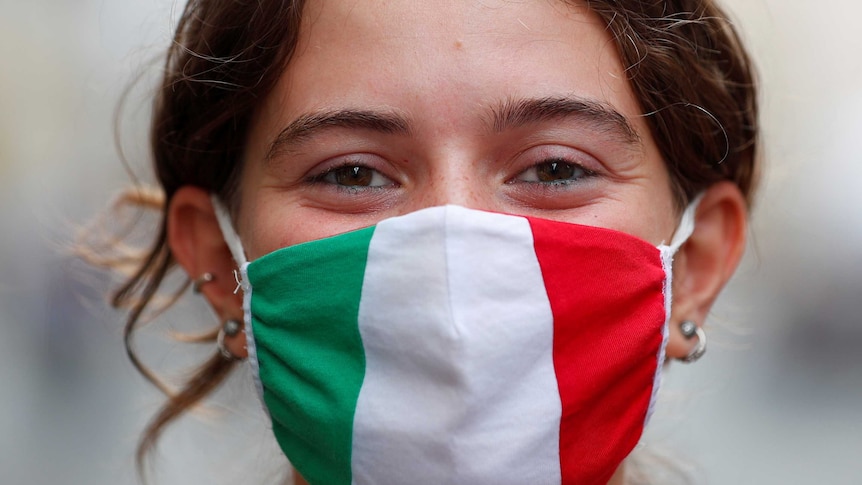 A woman's face wearing a mask with the colours of the Italian flag.
