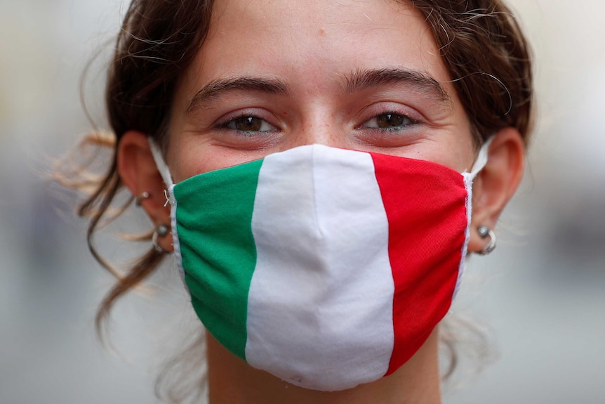 A woman's face wearing a mask with the colours of the Italian flag.