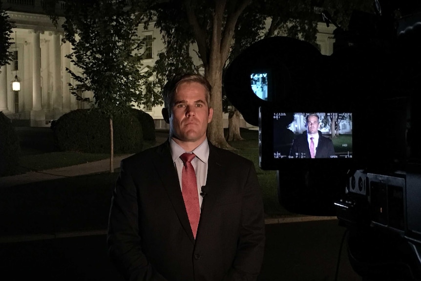 Duffy looking at TV camera while standing in front of the White House.