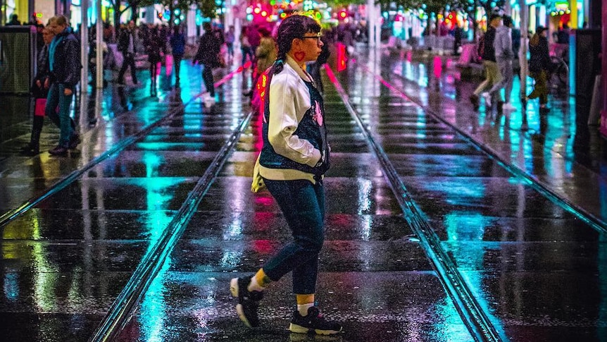 A person walks through Melbourne at night.