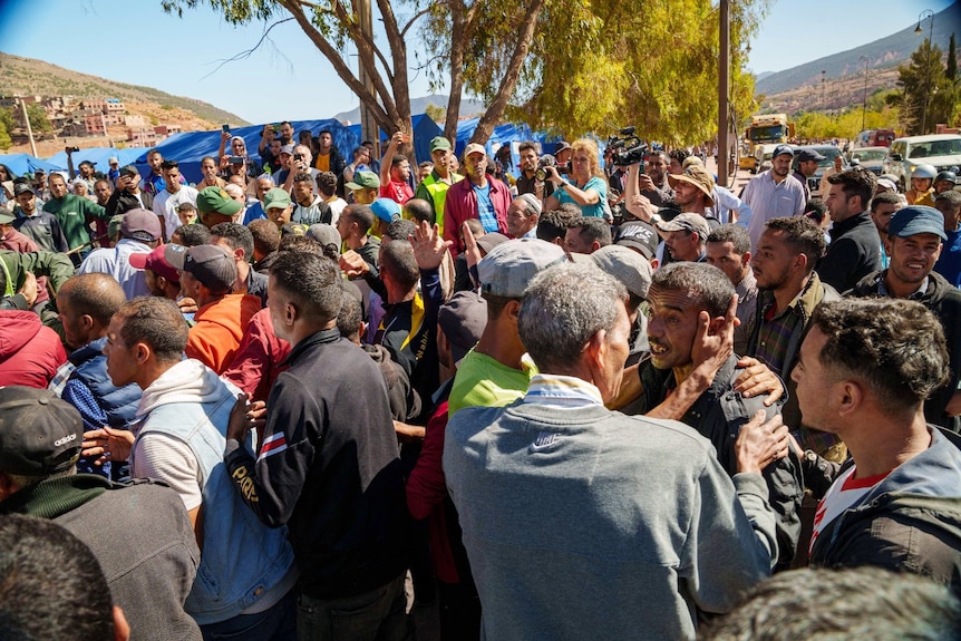 A large crowd, with several people in it looking angry