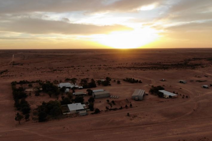 A household and sheds surrounded by trees and red dirt in the middle of outback South Australia