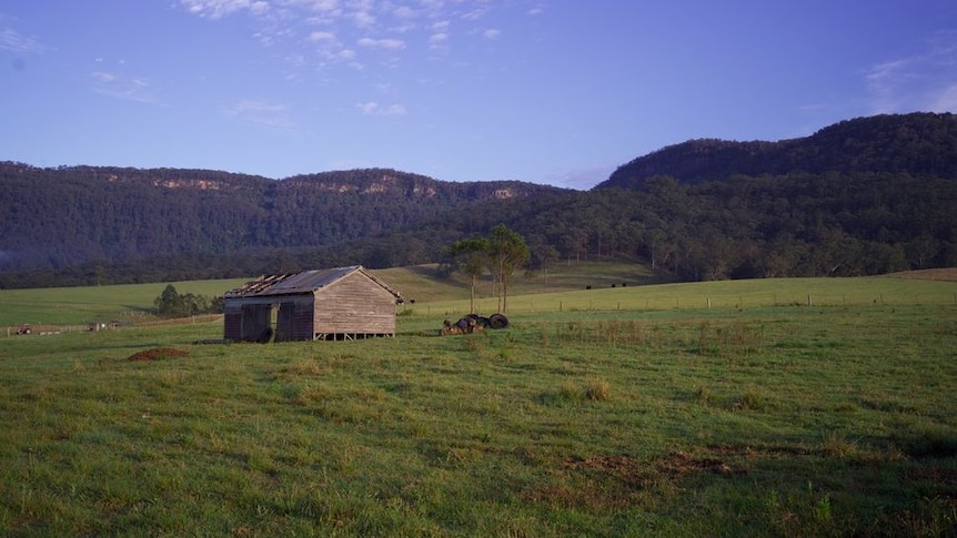 A farm house sitting in a green valley.