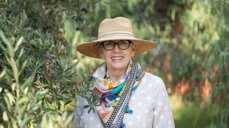 A lady smiling with a beige hat on and colourful scarf