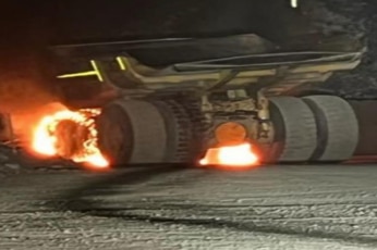 A large yellow dump truck on fire at a coal mine.