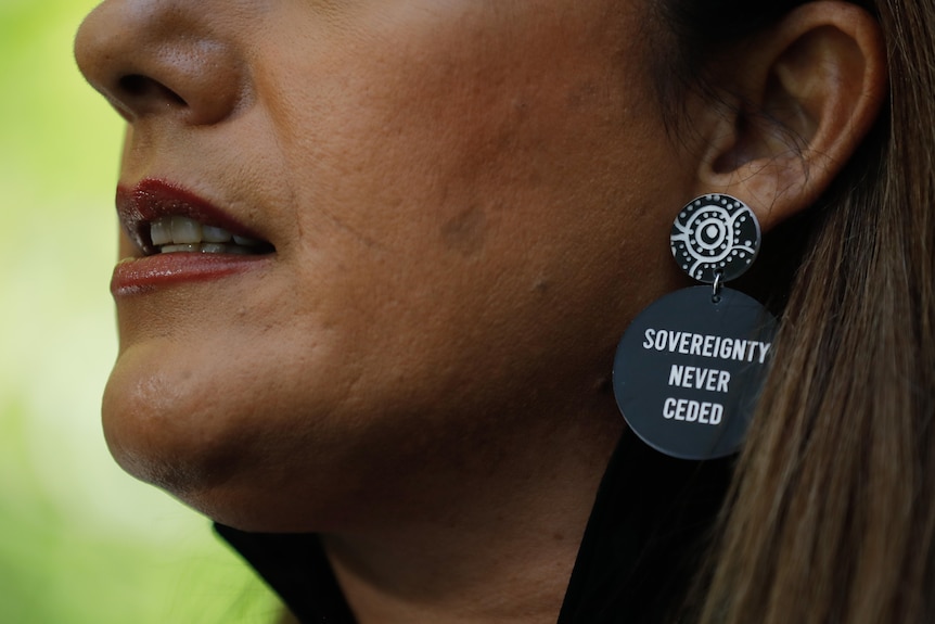 A close-up of Lidia Thorpes earrings that read 'sovereignty never ceded'. 