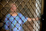 Woman looks out, the bars of the flyscreen door blocking her