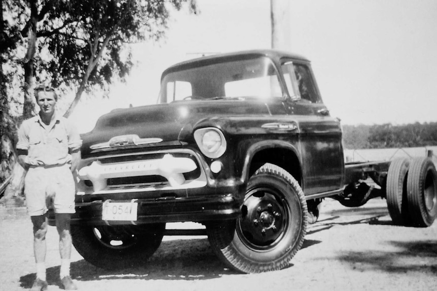 An old black and white photo of Norman Simon standing beside his Chev truck.