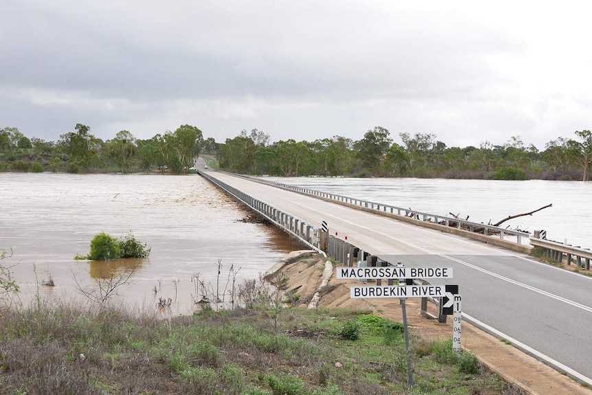 Floodwaters rise and swirl under the Macrossan Bridge on the Flinders Highway between Townsville and Charters Towers.