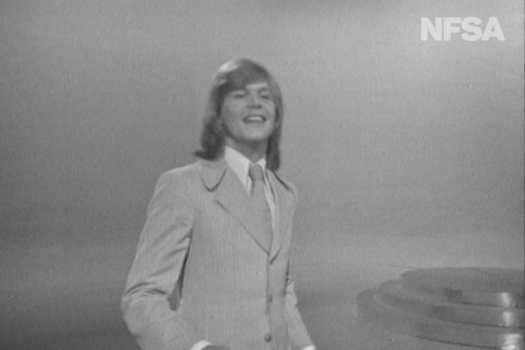 Black-and-white footage of John Farnham.