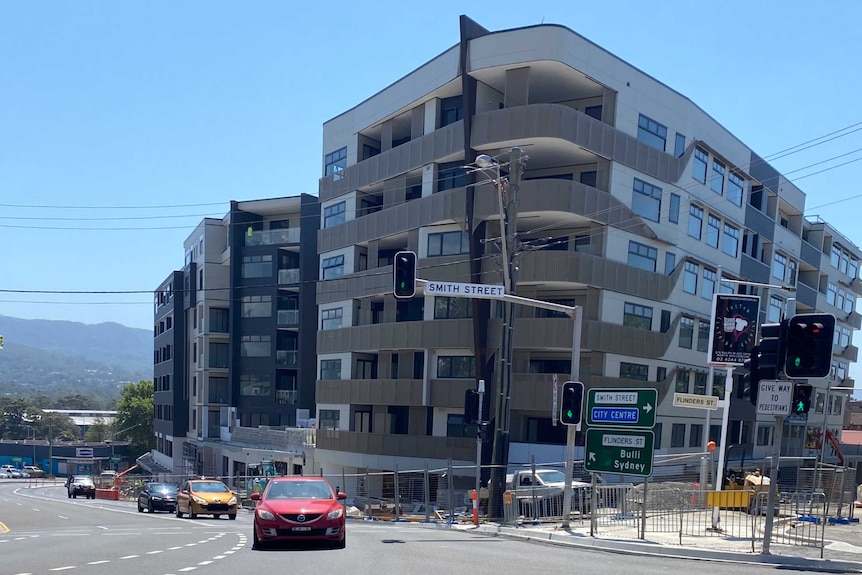 An apartment building under construction that appears quite different to a previous artists interpretation.