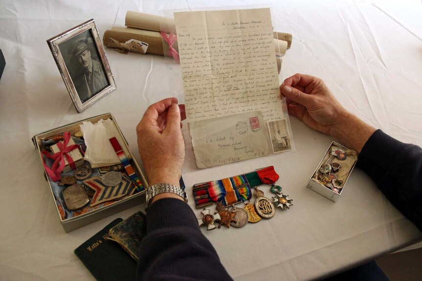 Hands hold a letter from the Elliott family collection in Tasmania which contains war memorabilia.