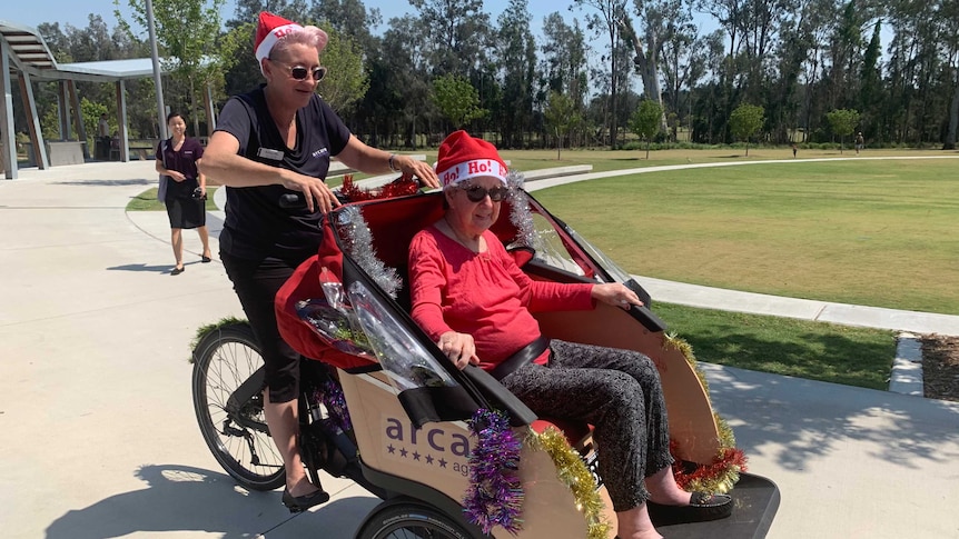 Aged care resident Jay Jones arrives in a Christmas themed tricycle to meet young pen pals