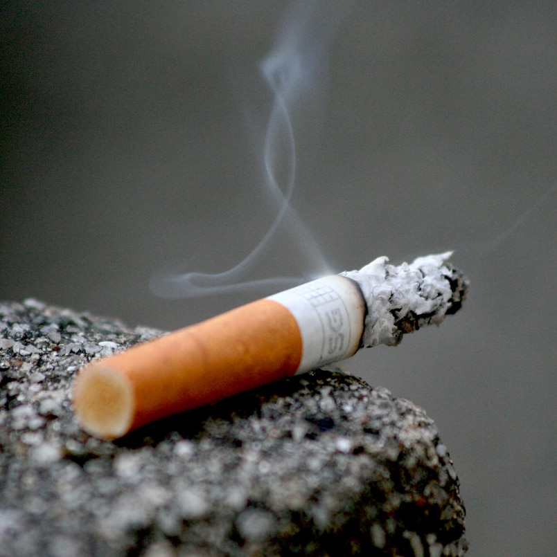 A burning cigarette resting on a ledge.