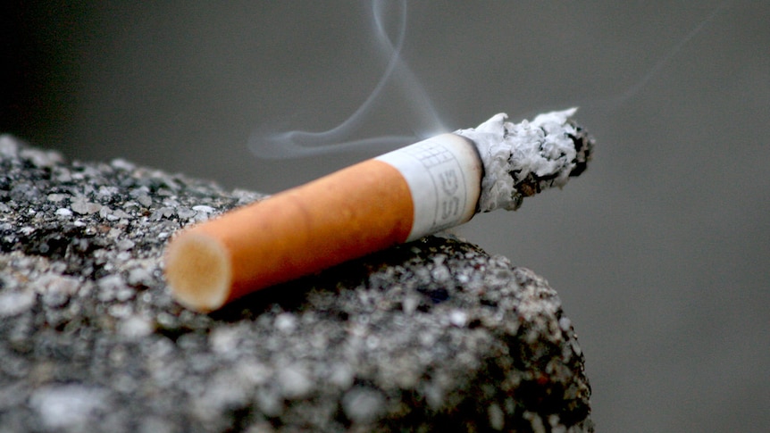 A burning cigarette resting on a ledge.