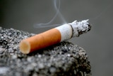 A burning cigarette on a ledge.
