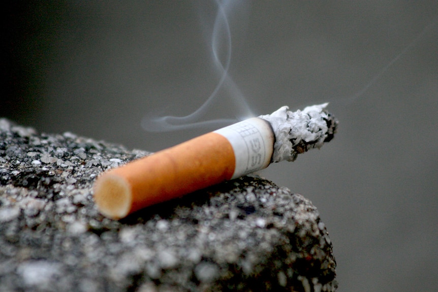 A burning cigarette resting on a ledge.