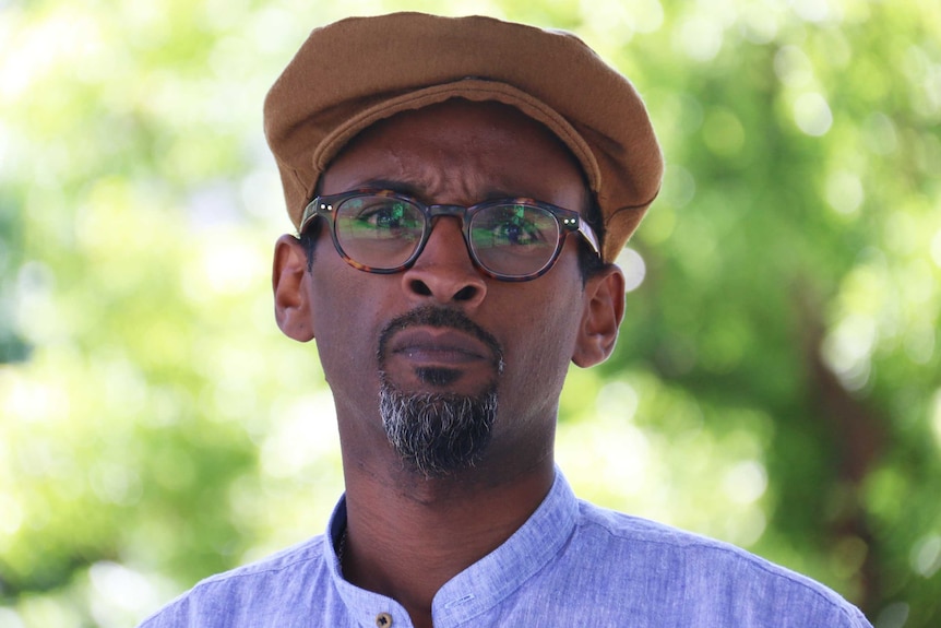 Nur Warsame wears a hat and glasses
