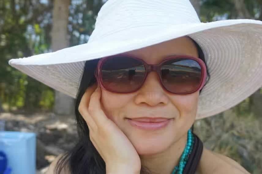 Close up of Cheng Lei smiling. She has a hat and sunglasses on.