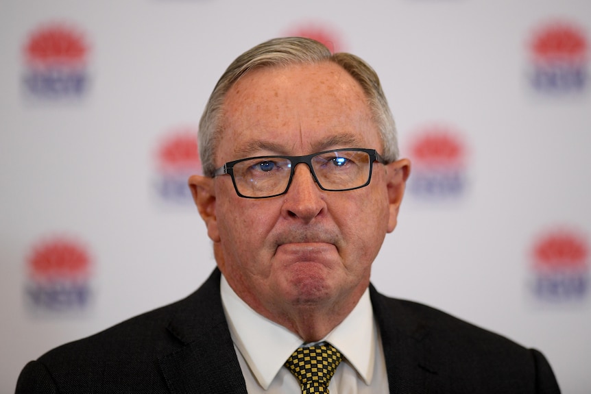 A man wearing glasses pursing his lips