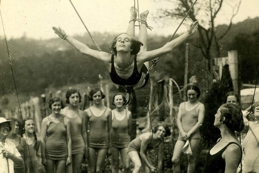 Black and white photo of a woman learning to dive with ropes attached to her feet