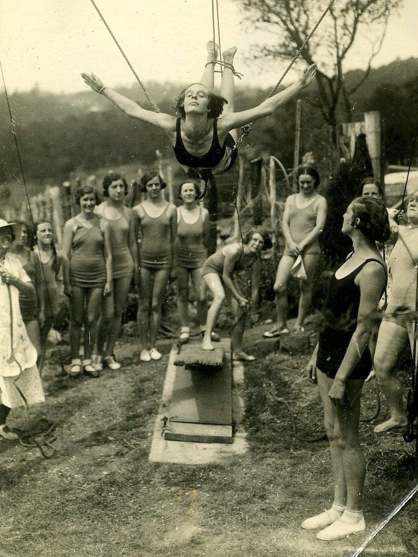 Black and white photo of a woman learning to dive with ropes attached to her feet