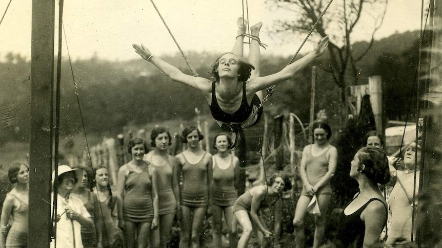 Black and white photo of a woman learning to dive with ropes attached to her feet