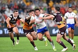 An NRL player runs with the ball, as three opponents attempt to tackle him