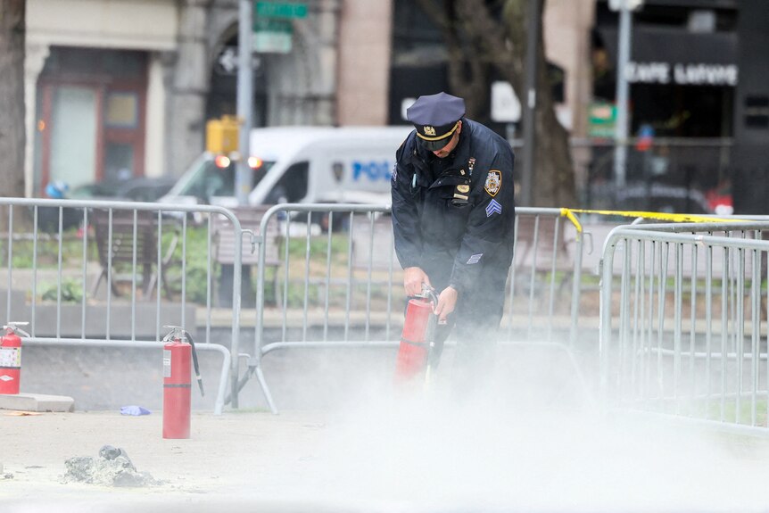 A police officer uses a fire extinguisher in a park