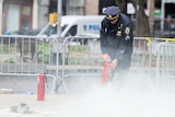 A police officer uses a fire extinguisher in a park