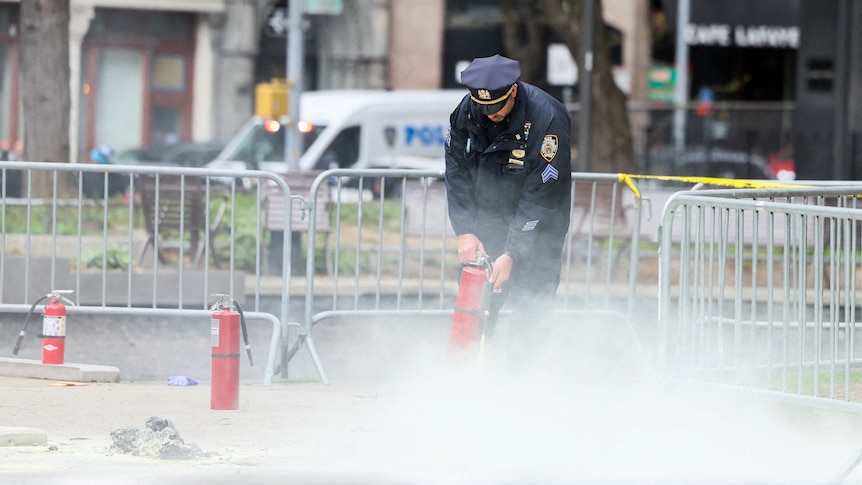 A police officer uses a fire extinguisher in a park