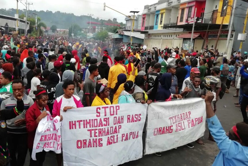 People display banners that read "Stop intimidation and racism towards indigenous Papuans" during a protest in Manokwari.
