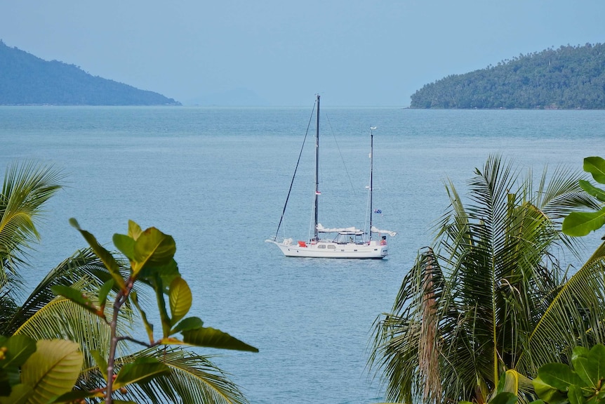 A white yacht on blue waters near tropical islands.