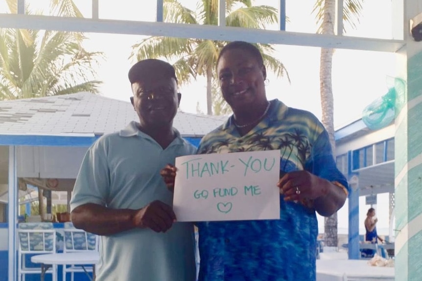 A photo of Maryann and Elvis Rolle holding a handwritten sign reading, 'Thank you Go Fund Me'.
