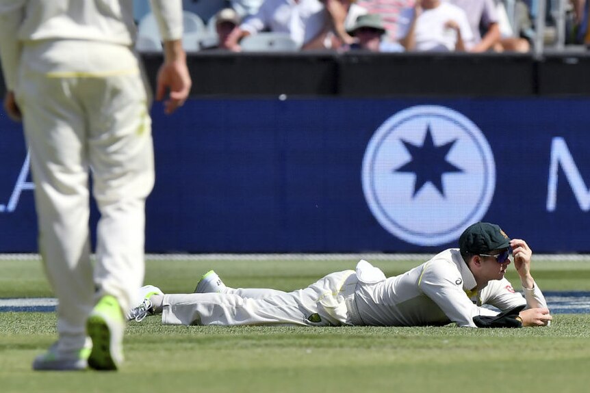 Australia's Steve Smith lays on the ground after dropping a catch