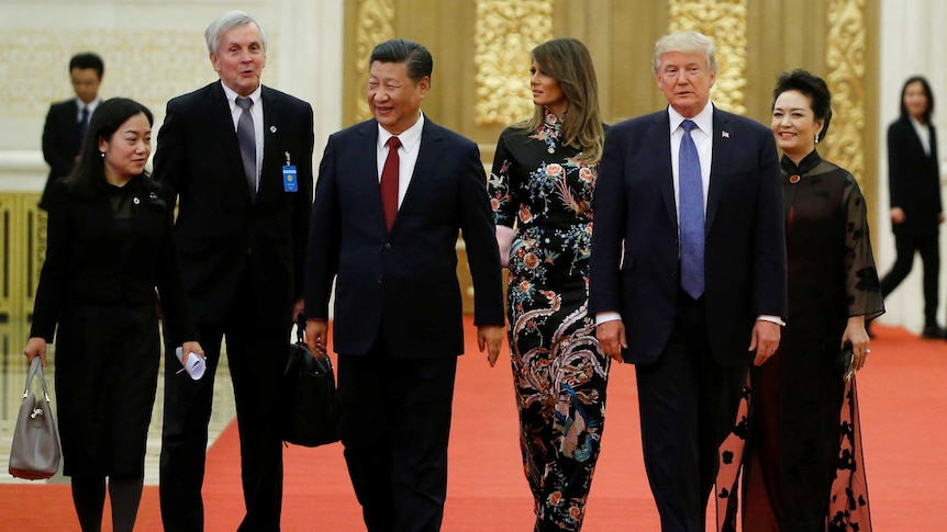 Donald Trump, Melania Trump, Xi Jinping and Peng Liyuan walk side-by-side on red carpet.