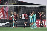 A Canadian women's footballer raises her arms running back from goal as the Matildas react in dejection.