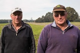Two men stand in a pastoral field
