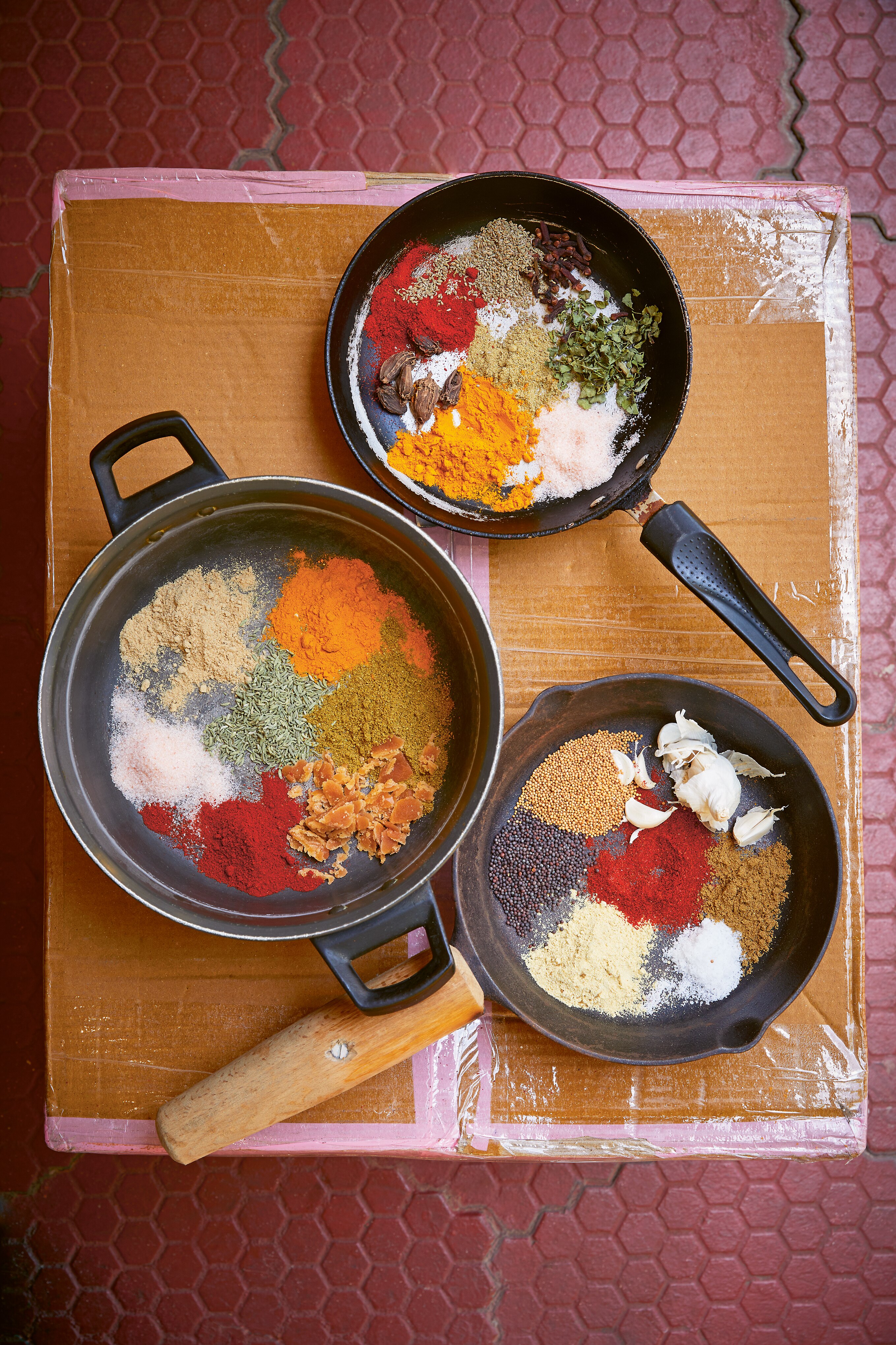 Three pans each containing seven piles of different spices.